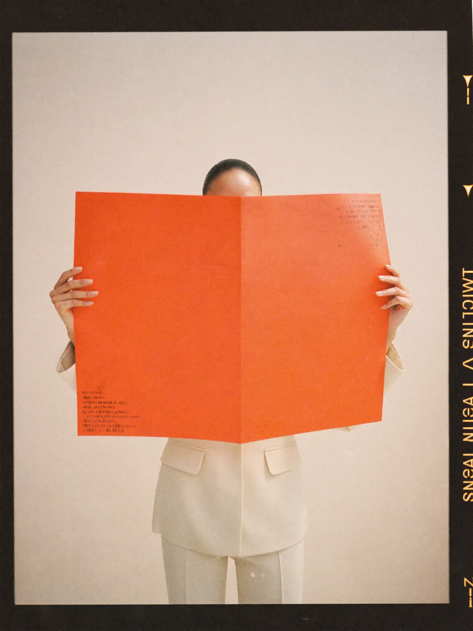 Woman in a cream suit holding an orange paper